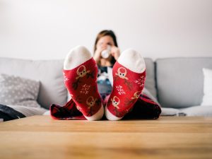 Woman drinking hot cocoa, has Christmas socks, enjoying the cooling air of her HVAC